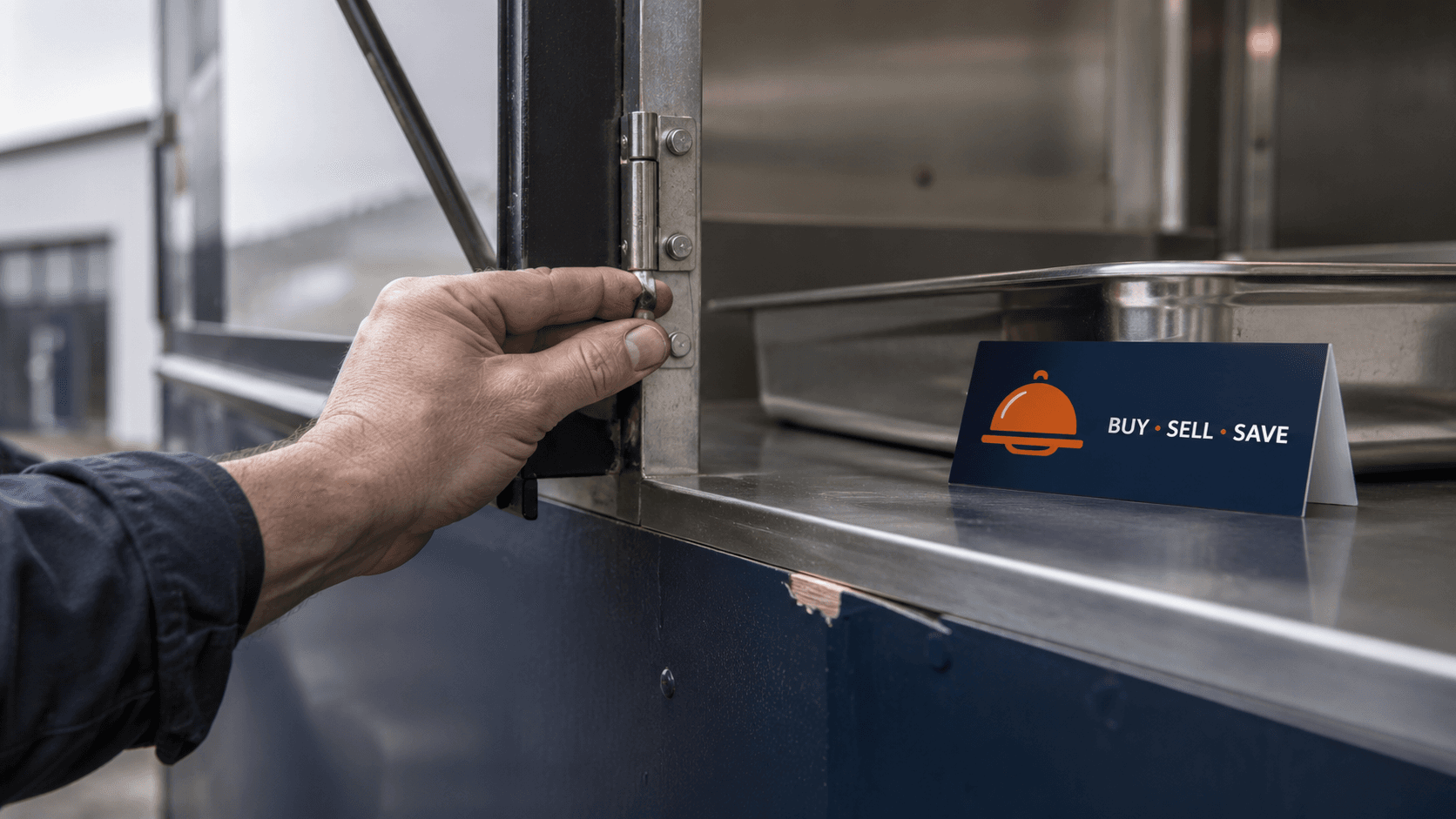 Close-up of a hand testing the hinge on a used catering trailer's serving hatch during a pre-purchase inspection.